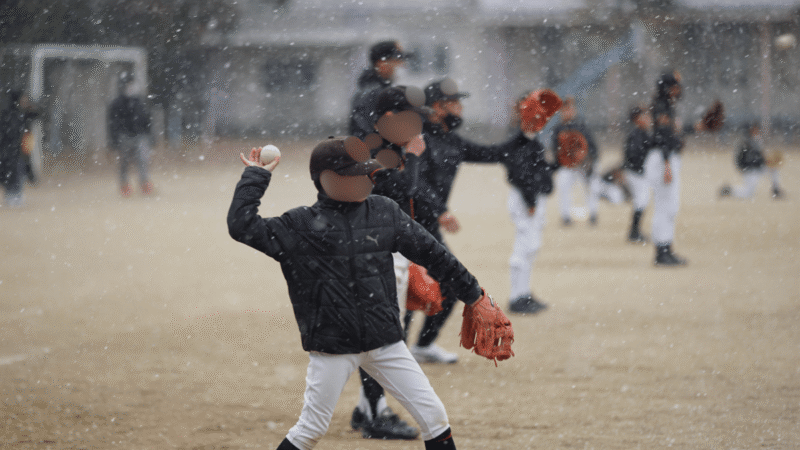 雪が吹き出した極寒のグラウンドでウォーミングアップする少年野球の選手たち