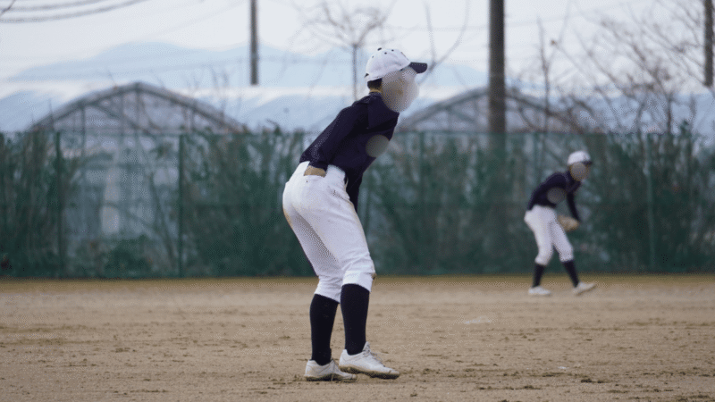 冬の寒い中、少しでも指先を温めようとポケットに手を入れている少年野球の選手
