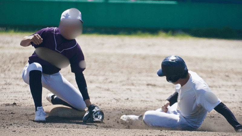 二塁ベースに足から滑り込む走者と、グラブを下ろしてタッチにいく野手